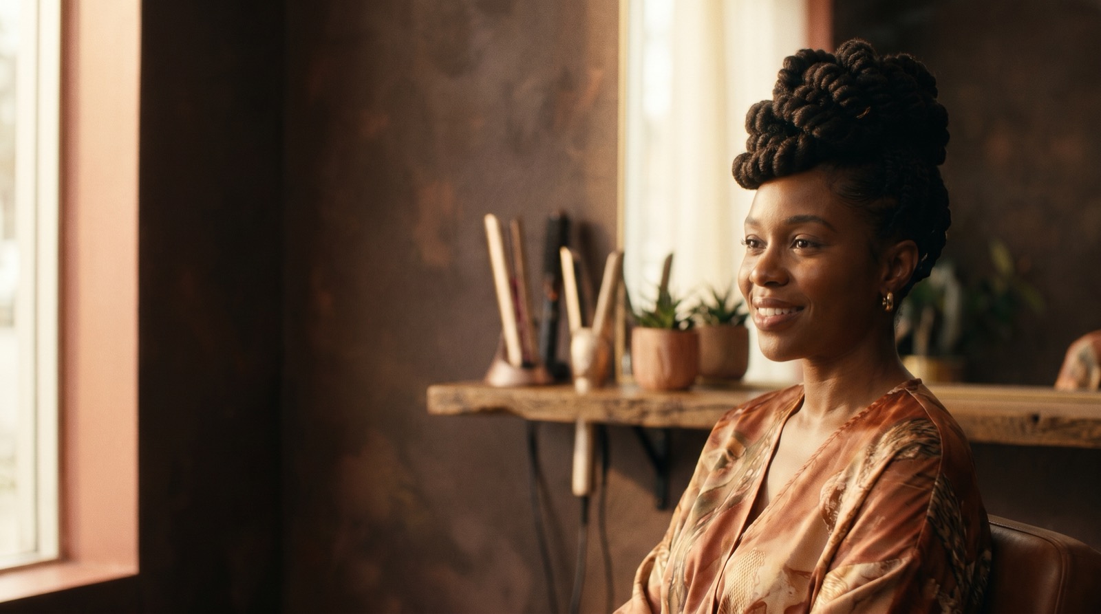Black woman with an elegant natural updo hairstyle, warm terracotta salon background